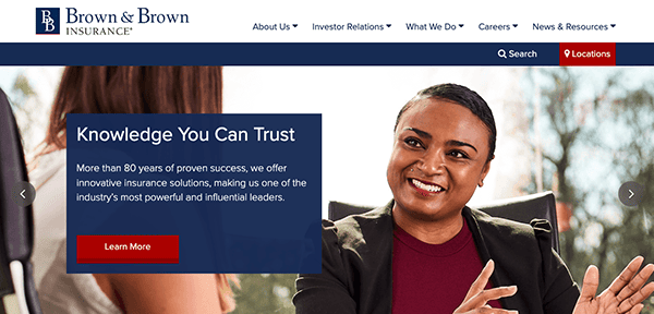 A confident professional woman is smiling and gesturing during a conversation in an office setting, with promotional text for brown & brown insurance emphasizing trust and experience in the foreground.