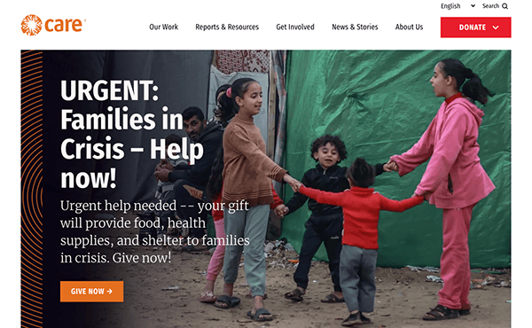 Children playing in a makeshift camp with an appeal for donations to help families in crisis.