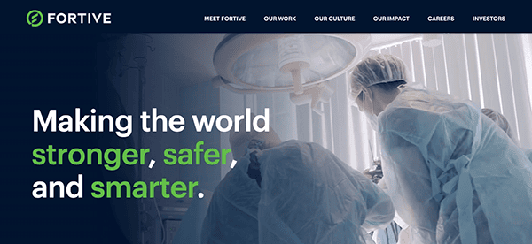 Healthcare professionals operating under surgical lights with a slogan about improving the world displayed above.