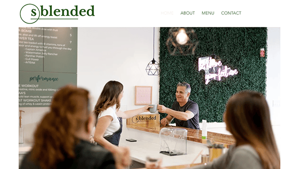 Customers being served at a modern cafe with a green wall and neon sign.