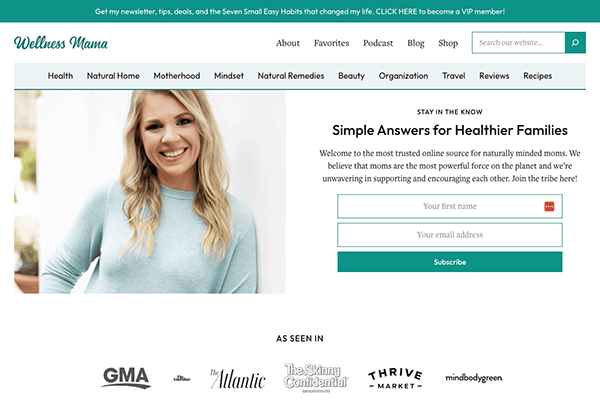 A screenshot of the "wellness mama" website homepage featuring a smiling woman, with sections for blog, podcast, and shop, and logos of media outlets that have featured the site.