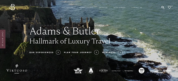 Website banner for adams & butler luxury travel, featuring an aerial view of a rocky coastline with ruins atop a cliff.