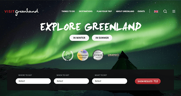 Website homepage for visit greenland featuring a navigation menu and an image of the northern lights over a snowy landscape, with interactive search options.