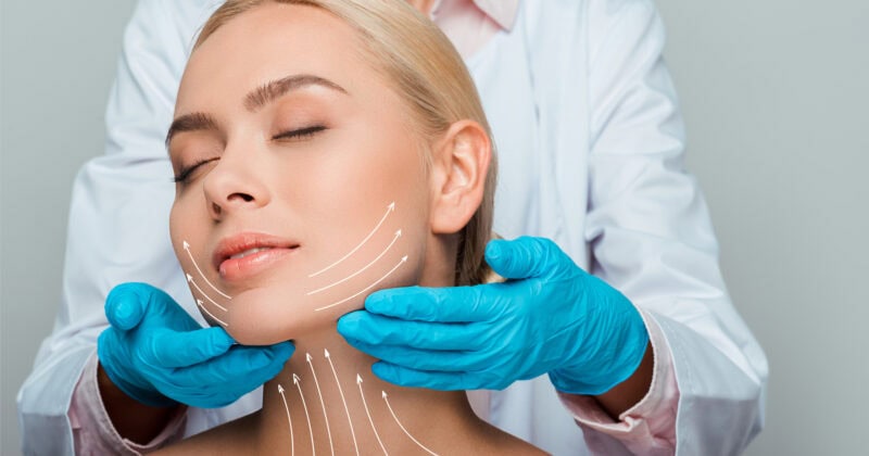 Doctor in gloves marking a woman's face for cosmetic surgery procedures, with focus on her relaxed expression. The best plastic surgeon ensures precision and comfort.