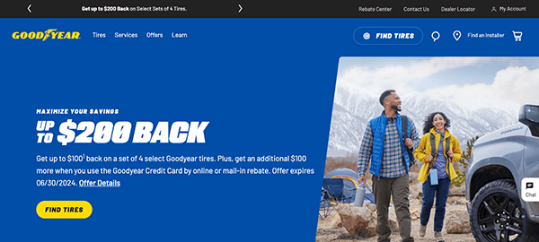 A couple stands beside an suv in a mountainous area, smiling, on a promotional banner for goodyear tires offering up to $200 back on tire purchases.