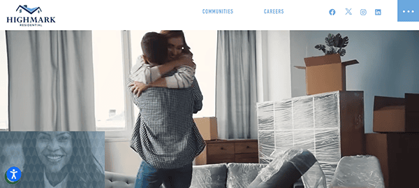 A man and woman embracing in a room full of unpacked boxes, suggesting they are moving into a new home.