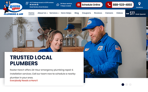 Two Rooter Hero plumbers in blue uniforms smile while working inside a home, demonstrating the service quality featured on the best plumbing websites. Website header and contact information are visible at the top of the page.