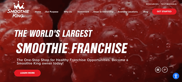 Website homepage of smoothie king with a close-up image of fresh strawberries as the background, featuring navigation links and promotional text about franchise opportunities.