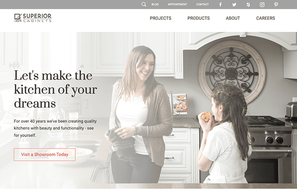 A woman smiles while talking to a young girl in a white kitchen. The text on the image promotes "Superior Cabinets" and encourages viewers to visit a showroom to see kitchen designs.