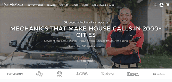 A mechanic standing with arms crossed near a car, promoting home service in 2000+ cities with 12-month/12,000 mile warranty. Logos of various media outlets like CBS, NBC, and Forbes are shown below.
