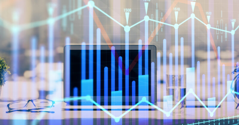 A laptop on a desk is surrounded by office items with overlaid charts and graphs representing financial data and KPIs for therapists, highlighting trends critical for private practice success.