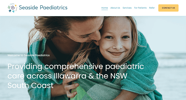A woman embraces a smiling child. The text overlaid on the image reads, "Providing comprehensive paediatric care across Illawarra & the NSW South Coast" for Seaside Paediatrics.