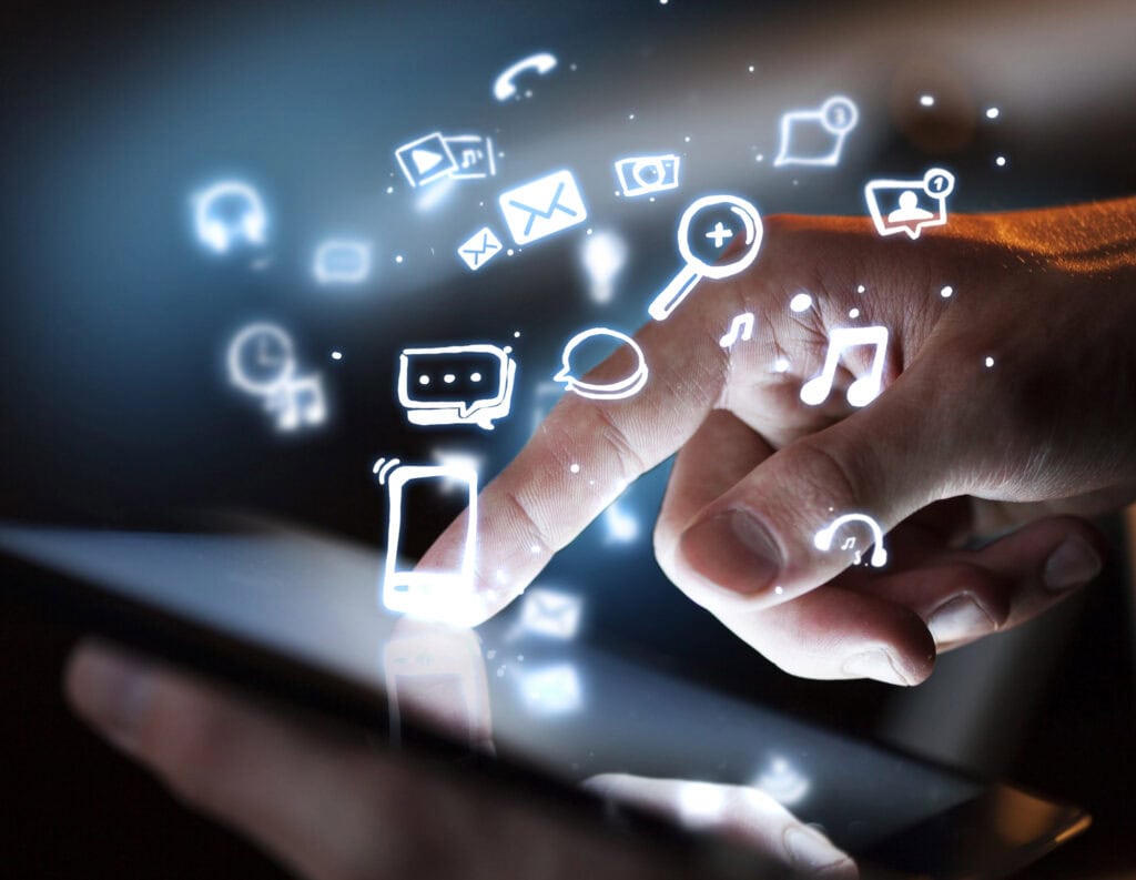 A hand interacts with a tablet screen, surrounded by glowing icons representing various apps and online services such as messaging, music, email, social media, and search.