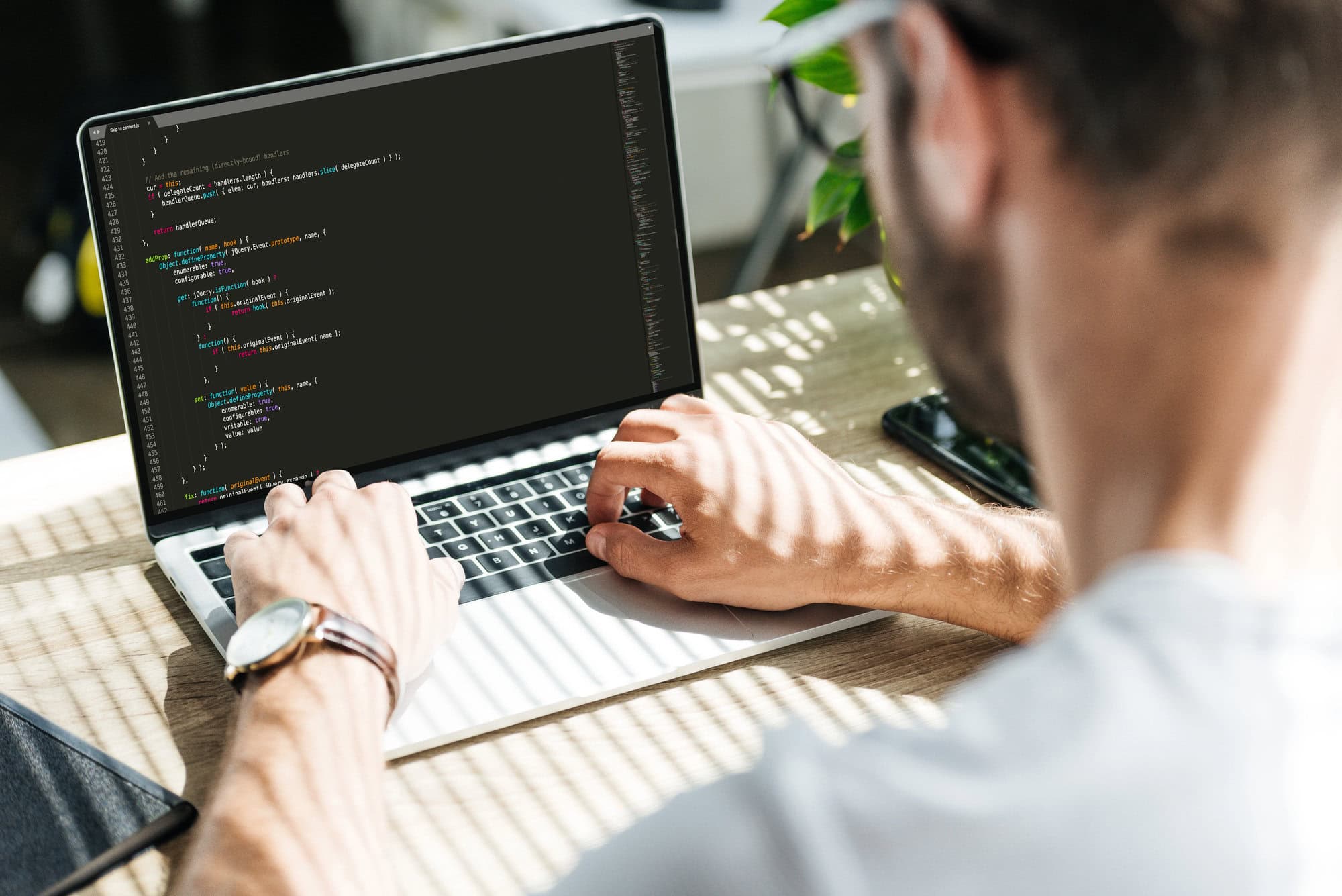 Person typing code on a laptop with a screen displaying a dark-themed code editor, ensuring ADA compliance services are seamlessly integrated.