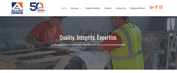 Two workers in safety gear are inspecting wooden beams. The Allied Electric logo and "50 Years" graphic grace the top, alongside a navigation menu, embodying the quality and integrity that define leading commercial electrician websites. Text proudly states: "Quality. Integrity. Expertise. Since 1973.