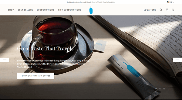 A glass of coffee on a saucer next to a packet of instant coffee sits on a table, accompanied by marketing text for travel-friendly craft coffee and a shop button inspired by the 20 Best Cafe Websites.