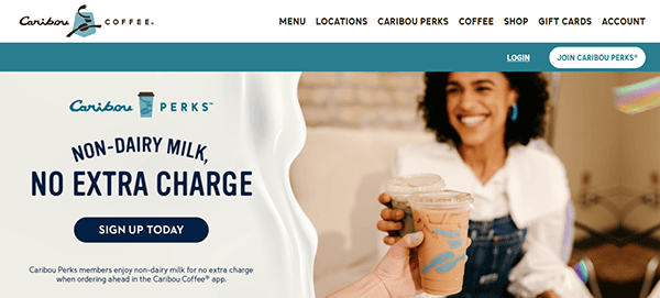 Website screenshot showcasing Caribou Coffee's standout Cafe Website Design, highlighting a promotion for non-dairy milk at no extra charge with signup. In the background, a woman is holding an iced coffee, perfectly capturing the essence of one of the Best Cafe Websites.