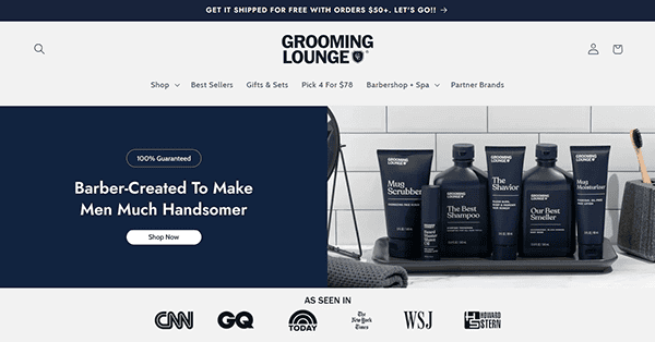 The Grooming Lounge homepage showcases top-tier men's grooming products artfully arranged on a tray, under the slogan "Barber-Created To Make Men Much Handsomer." As one of the best barber shop platforms online, media outlet logos proudly feature at the bottom.