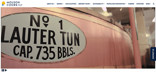 Inside a brewery with pinkish hues, a large metal lauter tun stands proudly marked "No. 1 Lauter Tun Cap. 735 BBLs," echoing the craftsmanship showcased on top beverage distributor websites.