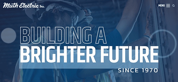 Two construction workers in safety gear collaborate on-site, while the text "Building a Brighter Future Since 1970" shines above, showcasing their dedication akin to the best commercial electricians in the business.