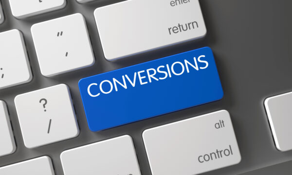 Computer keyboard with a blue key labeled "CONVERSIONS" among standard white keys, designed to drive conversions and increase ROI.