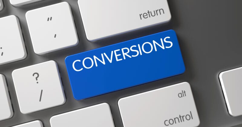 Computer keyboard with a blue key labeled "CONVERSIONS" among standard white keys, designed to drive conversions and increase ROI.