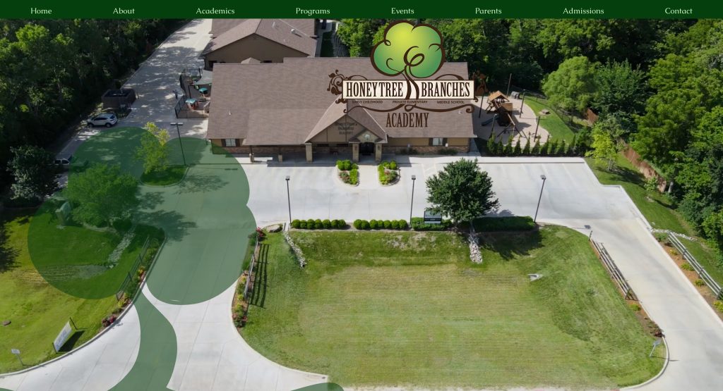 Aerial view of Honey Tree & Branches Academy, featuring a tan building surrounded by trees, a parking lot, and a large grassy area. The website navigation menu reflects thoughtful daycare website design at the top.