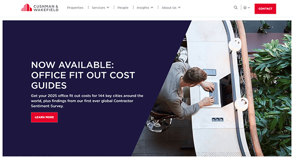 A person types on a laptop at a desk, engrossed in a Cushman & Wakefield webpage that showcases 2025 Office Fit Out Cost Guides info with a "Learn More" button. This real estate website is an invaluable resource for anyone navigating the best commercial real estate options.