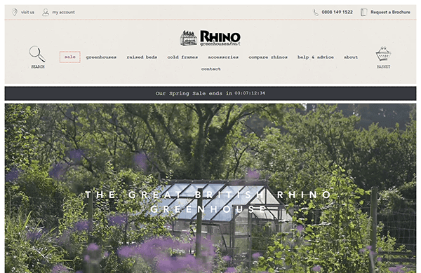 Screenshot of a website homepage for Rhino Greenhouses. Showcases a navigation menu, a banner image of a greenhouse in a garden, and a countdown timer for the spring sale, making it one of the top greenhouse sites.