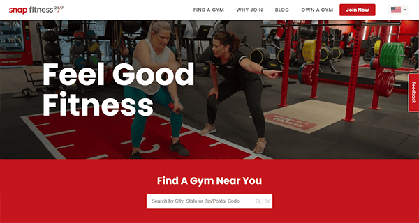Two women exercise inside a gym with weightlifting equipment. One coaches the other, who is squatting amidst the sleek layout reminiscent of the best gym websites. "Feel Good Fitness" is written in bold text, embodying top-tier gym website design.