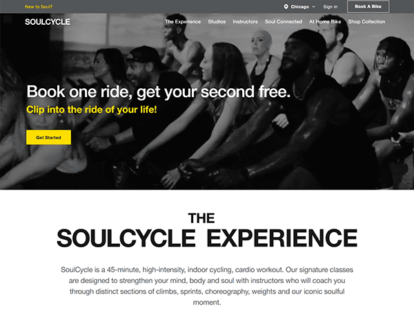 People in a cycling class at SoulCycle are exercising together, showcasing the dynamic energy captured on some of the best gym websites. A text overlay promotes a deal: "Book one ride, get your second free.