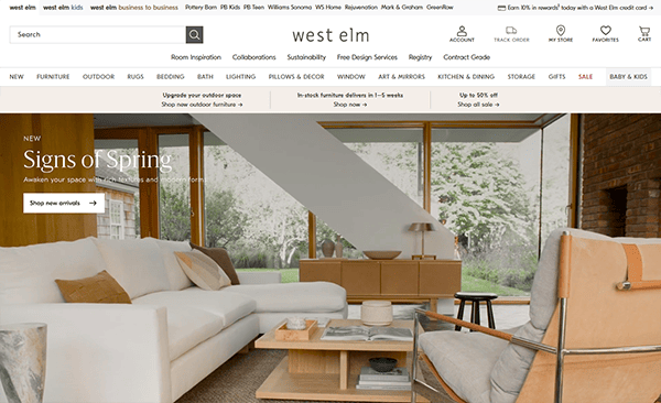 West Elm's homepage showcases a chic living room in neutral tones, featuring stylish furniture like a sofa, armchair, and coffee table beneath large windows. The header provides easy navigation links and flaunts their "Signs of Spring" banner—a perfect touch for your online furniture shopping journey.