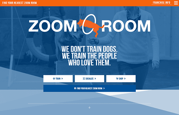 The Zoom Room homepage showcases the slogan: "We don't train dogs. We train the people who love them." This dog training website features navigation buttons for training, socializing, and shopping.