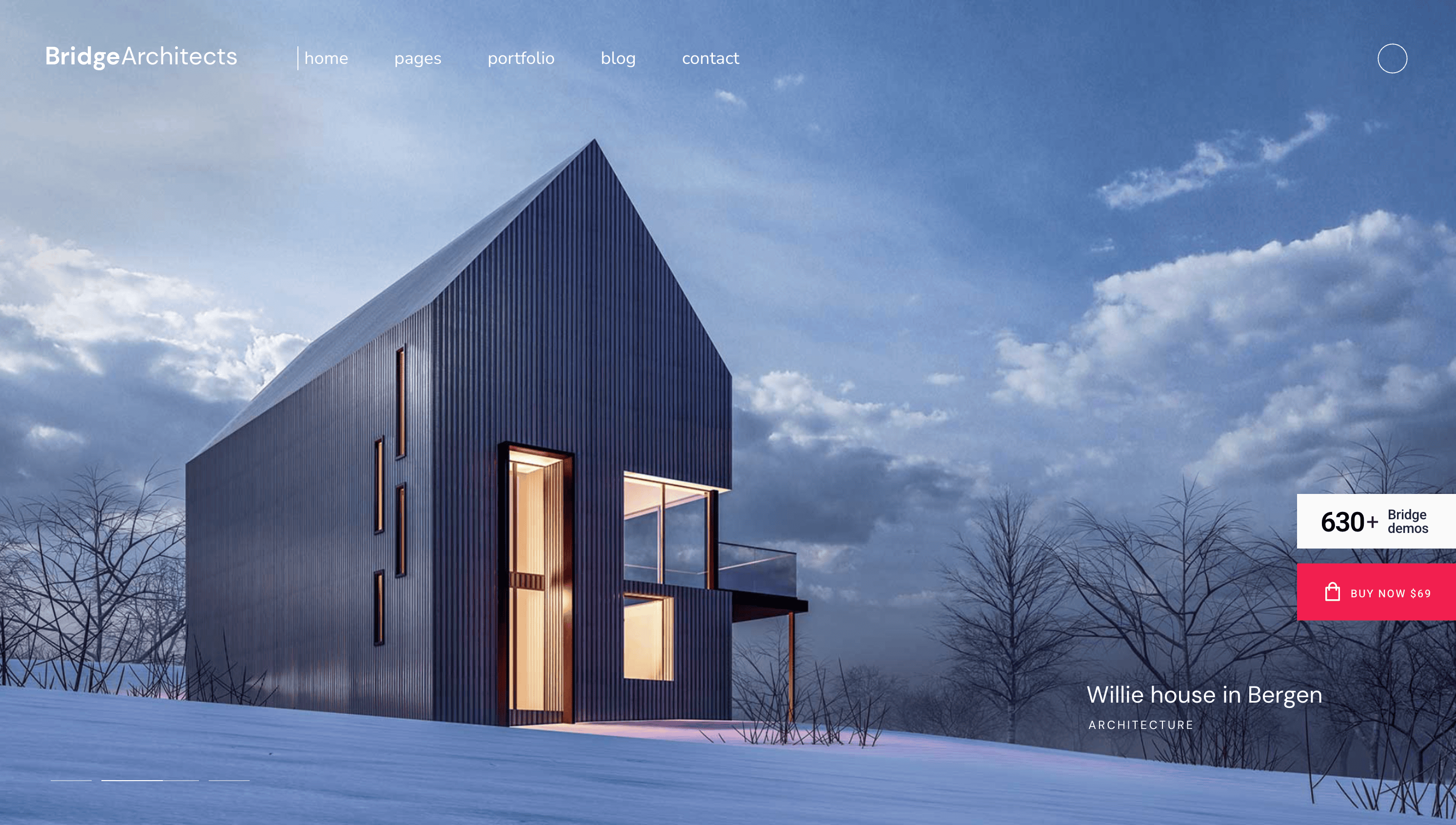 Modern, angular house with large windows, standing in a snowy landscape under a cloudy sky.