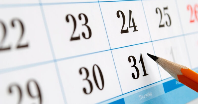 A pencil pointing at the 31st on a close-up view of a calendar page.