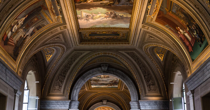 Step into an ornate interior where decorative arches and ceiling paintings tell historical tales, enhanced by intricate moldings and classical elements. Discover this masterpiece through the best museum websites, where stunning visuals meet seamless exploration.