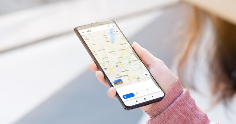 A person holds a smartphone displaying a digital map application, highlighting how businesses can improve Google Maps rankings and boost visibility through local SEO strategies in a city area.