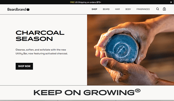 A person holds a round bar of soap with running water over a sink; text promotes Beardbrand’s charcoal-based Utility Bar, featured among the best small business websites for quality grooming essentials.