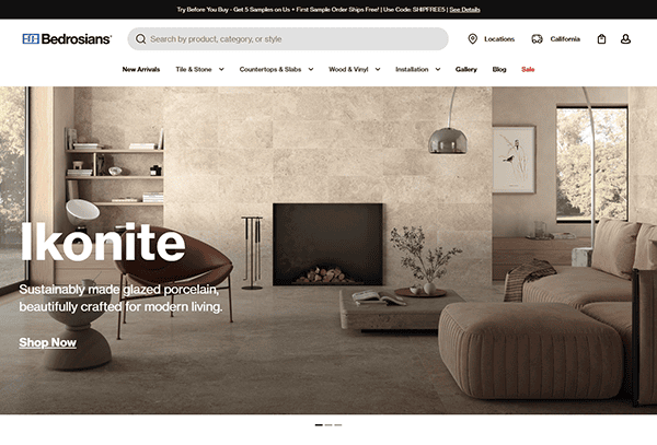 Modern living room with beige stone tile walls and floors, minimalist furniture, a fireplace, armchair, ottoman, and pendant lights; discover the best tile design with Bedrosians Ikonite in this stunning product ad.