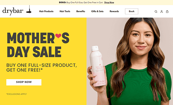 Woman holding a Drybar hair product bottle; text reads “Mother’s Day Sale: Buy one full-size product, get one free!” on a yellow background—perfect inspiration for the best salon websites and standout salon website design.
