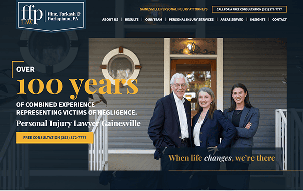 Three professionally dressed people, two women and one man, stand smiling in front of a house; text promotes a Gainesville personal injury law firm—featured on the best personal injury websites—with over 100 years of combined experience.