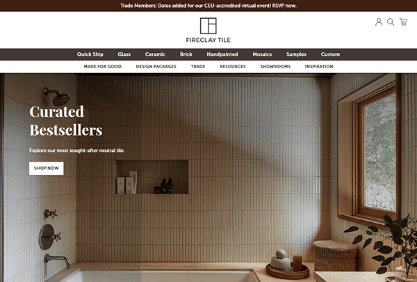 A modern bathroom with vertical white tile walls, a bathtub, sunlight streaming through the window, and a side table with decor—featured on one of the best tile websites for inspiring tile design: Fireclay Tile.