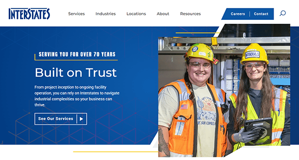 Two workers in safety gear smile on the best website promoting industrial services. Text reads "Built on Trust" and highlights over 70 years of service. Company logo "INTERSTATES" at the top, emphasizing their expertise as industrial electricians.