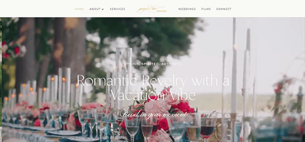 A long outdoor table is elegantly set with glassware, tall candles, and floral centerpieces, offering inspiration for wedding website ideas, with trees and a body of water visible in the background.