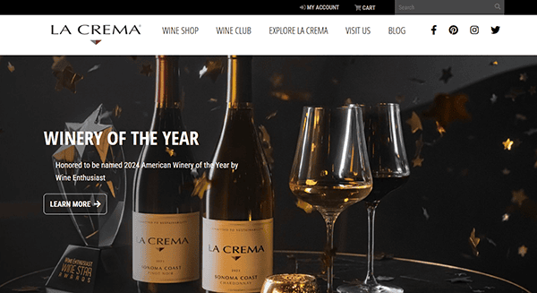 Two bottles of La Crema wine, two wine glasses, and an award are displayed on a table with gold star confetti, showcasing La Crema as Winery of the Year and inspiring standout winery website design.
