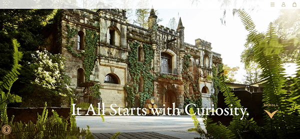 Historic stone building covered in ivy with large arched windows and doors, surrounded by greenery—a perfect inspiration for stunning winery website design. Text overlay reads, “It All Starts with Curiosity.”.