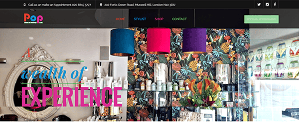 Colorful salon interior with vibrant hanging lamps, floral wallpaper, product shelves, and a "wealth of EXPERIENCE" text overlay—perfect inspiration for the best salon websites.