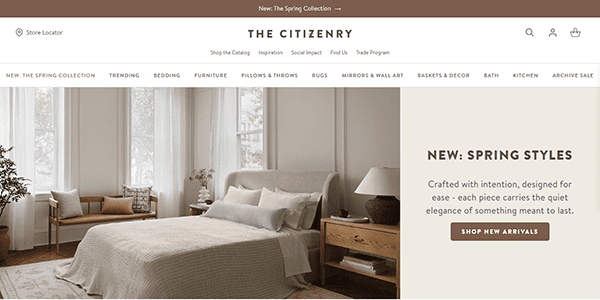 A neutral-toned bedroom with a bed, lounge chair, and large windows is shown on The Citizenry website—an inspiring example of Best Small Business Websites—highlighting new spring styles with a “Shop New Arrivals” button.