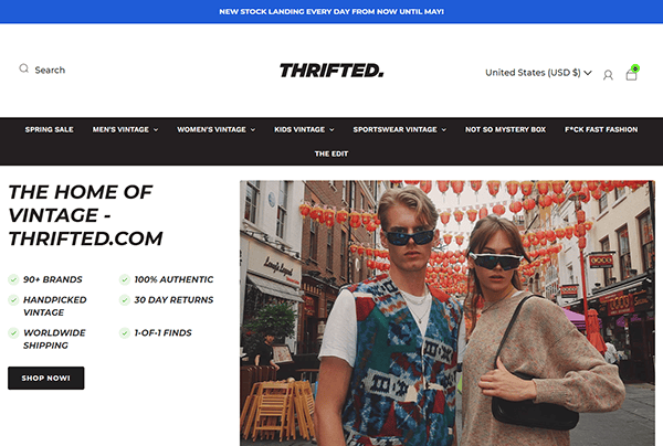 Screenshot of Thrifted.com homepage featuring two people in sunglasses, vintage clothing, and a banner announcing new stock arriving daily—showcasing why it’s among the best vintage clothing websites. Navigation bar and product features are visible.