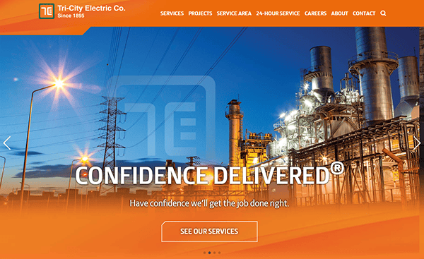 The homepage of Tri-City Electric Co. showcases industrial infrastructure and power lines, embodying the essence of top-tier Industrial Electrician Websites. With the slogan "Confidence Delivered," explore more with a conveniently placed button labeled "See Our Services.